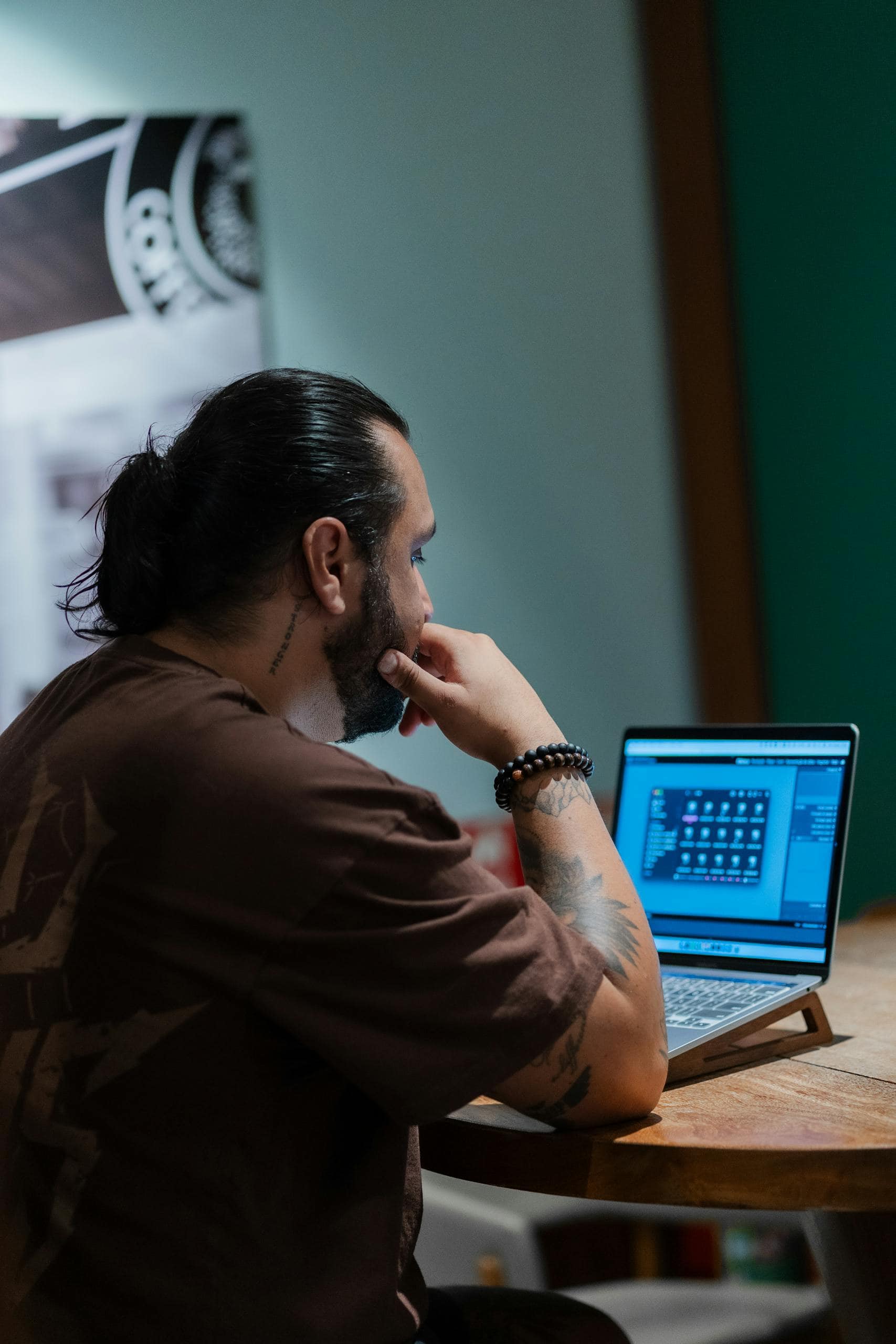 Man seated at a cafe table working on a laptop, focused on his screen.